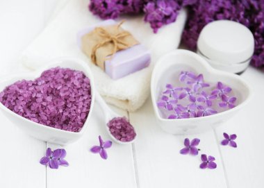 Spa havlu ve beyaz ahşap zemin üzerinde eflatun çiçekler ürünlerle Masaj