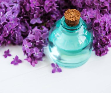 Beyaz ahşap zemin üzerinde eflatun çiçekli uçucu yağ