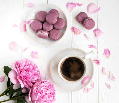 Kahve ve bir beyaz tahta masada macarons pembe şakayık