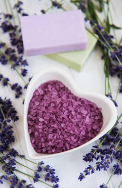 Deniz tuzu, sabun ve taze lavanta çiçekleri beyaz bir arka plan üzerinde kalp şeklinde bir kase