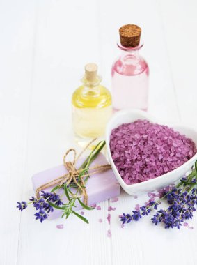 Deniz tuzu, uçucu yağlar, sabun ve taze lavanta çiçekleri ahşap arka plan üzerinde kalp şeklinde bir kase