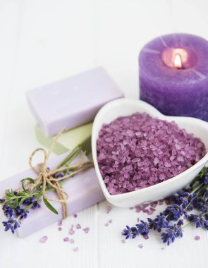 Deniz tuzu, mum, sabun ve taze lavanta çiçekleri ahşap arka plan üzerinde kalp şeklinde bir kase