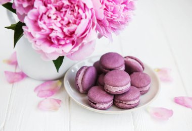Beyaz ahşap bir masa üzerinde macarons ile pembe şakayık