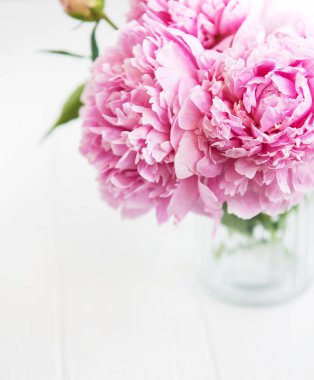 Beyaz ahşap bir masa üzerinde pembe şakayık çiçekli vazo