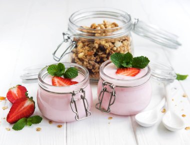 Sağlıklı Kahvaltı, yoğurt, taze çilek ve granola Beyaz ahşap bir masa üzerinde