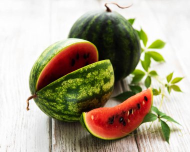 Eski ahşap bir masa üzerinde yeşil yaprakları ile karpuz