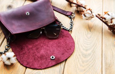 Ahşap arka plan üzerinde deri çanta ve pamuk çiçek