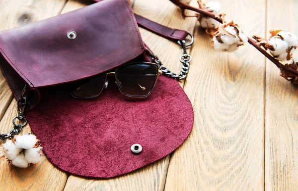 Ahşap arka plan üzerinde deri çanta ve pamuk çiçek