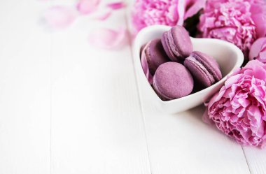 Pembe şakayık çiçekleri Beyaz ahşap bir masa üzerinde macarons ile