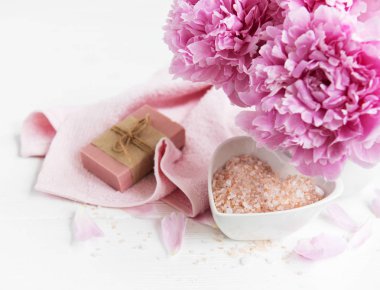 kalıp el yapımı sabun, yumuşak havlu ve bir beyaz tahta masaya peony çiçek