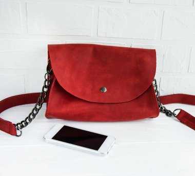 Kırmızı deri çanta ve ahşap bir masa telefonu