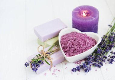 Deniz tuzu, mum, sabun ve taze lavanta çiçekleri ahşap arka plan üzerinde kalp şeklinde bir kase