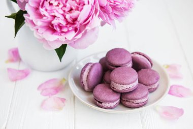 Beyaz ahşap bir masa üzerinde macarons ile pembe şakayık