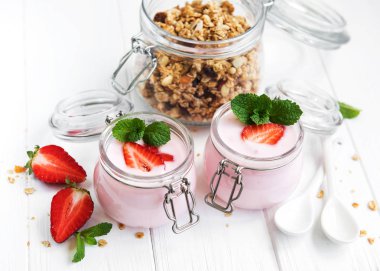 Sağlıklı Kahvaltı, yoğurt, taze çilek ve granola Beyaz ahşap bir masa üzerinde