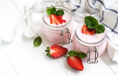 Kavanoz bir beyaz tahta masada çilekli yoğurt ile