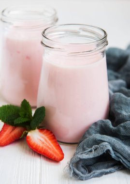 Kavanoz bir beyaz tahta masada çilekli yoğurt ile