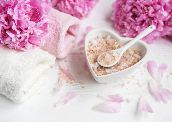 Massage salt and peony flowers on a white wooden background