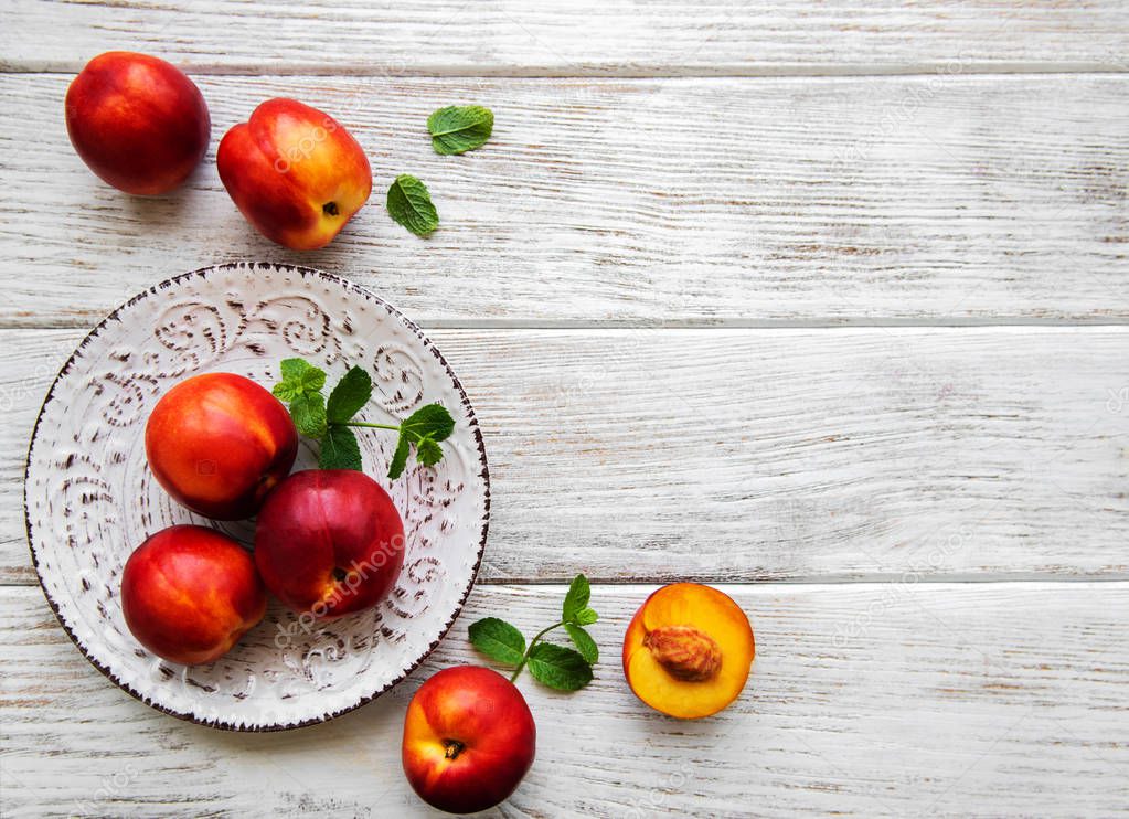 Plate with fresh nectarines on a white wooden table
