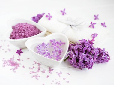 Spa havlu ve beyaz ahşap zemin üzerinde eflatun çiçekler ürünlerle Masaj