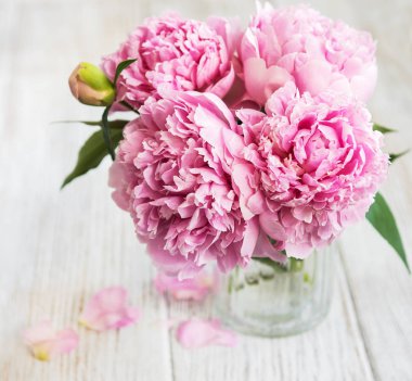 Beyaz ahşap bir masa üzerinde pembe şakayık çiçekli vazo