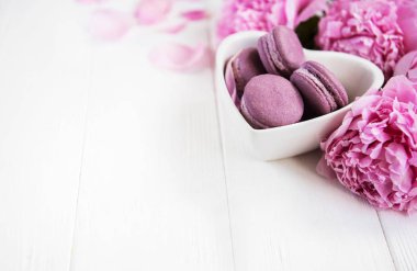 Pembe şakayık çiçekleri Beyaz ahşap bir masa üzerinde macarons ile
