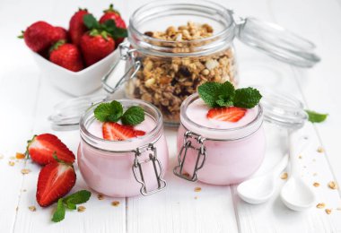 Sağlıklı Kahvaltı, yoğurt, taze çilek ve granola Beyaz ahşap bir masa üzerinde