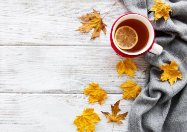 ahşap zemin ile bir fincan çay ve kuru düşen sarı yapraklar üzerinde sonbahar flatlay 