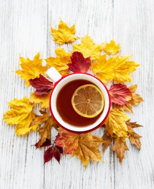 ahşap zemin ile bir fincan çay ve kuru düşen sarı yapraklar üzerinde sonbahar flatlay 