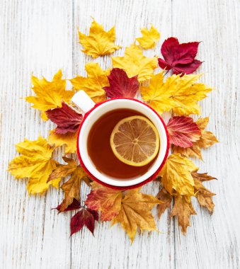 ahşap zemin ile bir fincan çay ve kuru düşen sarı yapraklar üzerinde sonbahar flatlay 