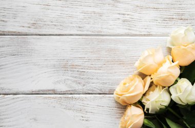 Eski ahşap bir masa üzerinde sarı ve beyaz güller