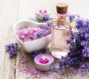 Deniz tuzu, petrol ve taze lavanta çiçekleri eski ahşap arka plan üzerinde kalp şeklinde bir kase