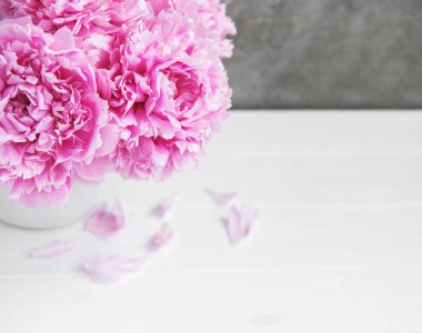 Beyaz ahşap bir masa üzerinde pembe şakayık çiçekli vazo