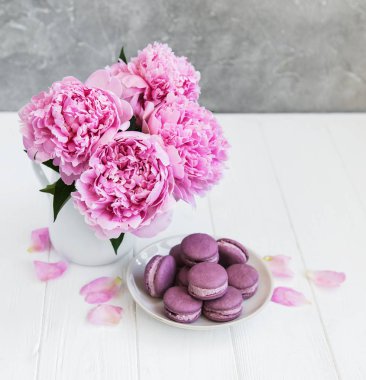 Beyaz ahşap bir masa üzerinde macarons ile pembe şakayık