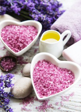 Deniz tuzu, yağlar, sabun ve taze lavanta çiçekleri ahşap arka plan üzerinde kalp şeklinde bir kase