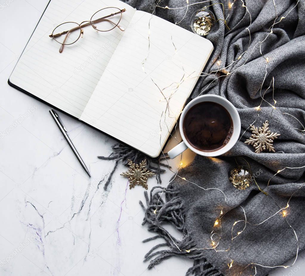 Notebook,  scarf, coffee  and garland on a marble backgroun