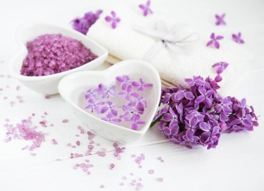 Spa havlu ve beyaz ahşap zemin üzerinde eflatun çiçekler ürünlerle Masaj