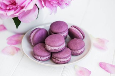 Beyaz ahşap bir masa üzerinde macarons ile pembe şakayık
