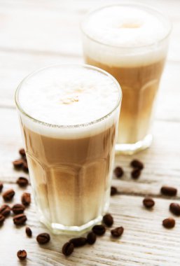 İki bardak latte kahve ve kahve çekirdekleri eski bir ahşap tablo