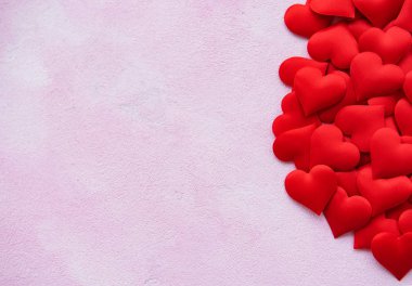 Pembe bir beton zemin üzerine kırmızı ipek kalpler