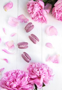 Pembe şakayık çiçekleri Beyaz ahşap bir masa üzerinde macarons ile
