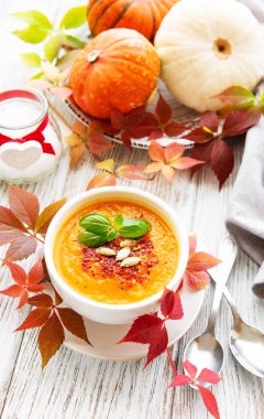 Rustik ahşap arka plan üzerinde kase kabak çorbası, Taze kabak ve sonbahar yaprakları