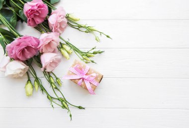 Taze pembe eustoma çiçek ve hediye kutusu ahşap arka plan üzerinde