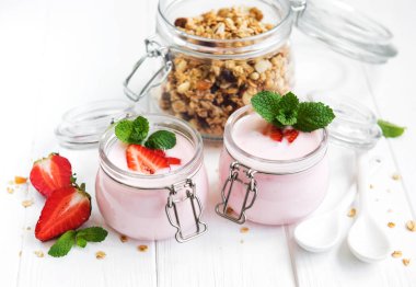 Sağlıklı Kahvaltı, yoğurt, taze çilek ve granola Beyaz ahşap bir masa üzerinde