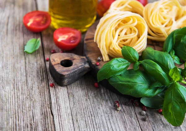 İtalyan gıda maddeleri - makarna, domates, fesleğen ve zeytinyağı eski bir ahşap tablo