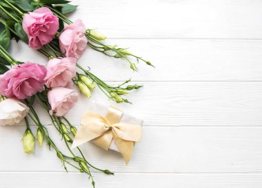 Taze pembe eustoma çiçek ve hediye kutusu ahşap arka plan üzerinde