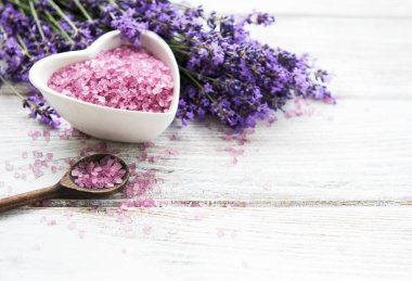Deniz tuz ve taze lavanta çiçekleri ahşap arka plan üzerinde kalp şeklinde kaseyle