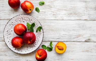 Beyaz ahşap bir masa üzerinde taze nektarin plakalı