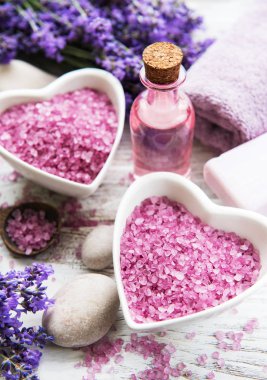 Deniz tuzu, yağlar, sabun ve taze lavanta çiçekleri ahşap arka plan üzerinde kalp şeklinde bir kase