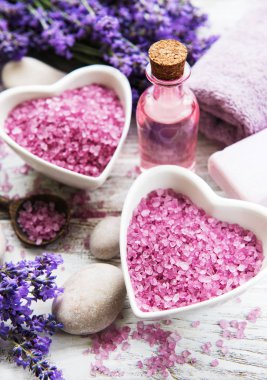 Deniz tuzu, yağlar, sabun ve taze lavanta çiçekleri ahşap arka plan üzerinde kalp şeklinde bir kase