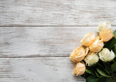 Eski ahşap bir masa üzerinde sarı ve beyaz güller